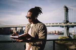 african american man in wireless earphones with organizer on bridge