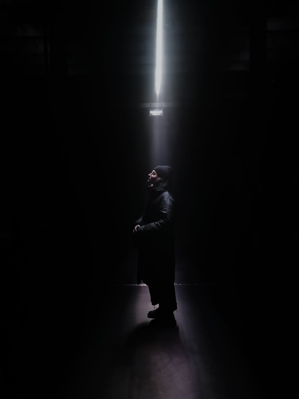 black photograph of a man standing in a beam of light